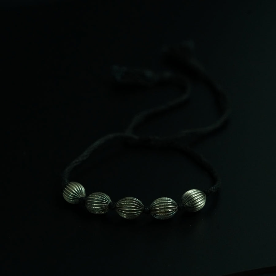 a bracelet with three silver balls on a black surface