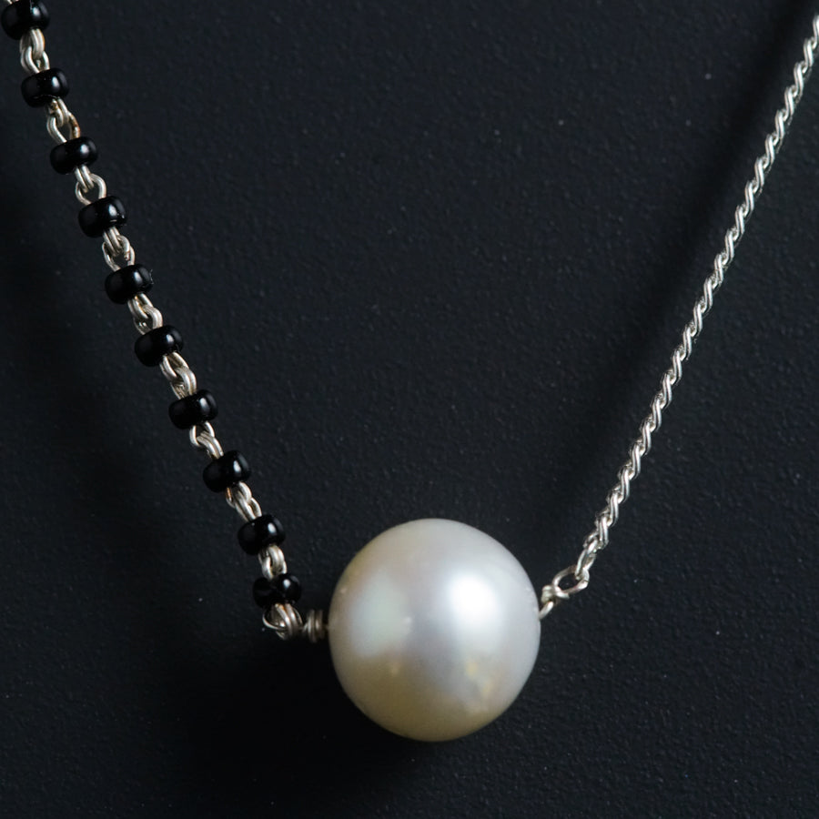 a white pearl on a black beaded necklace