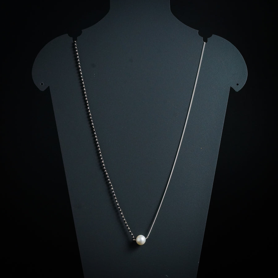 a necklace with a pearl hanging from it