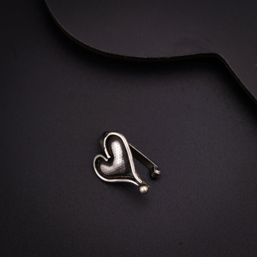 a heart shaped brooch sitting on top of a black surface