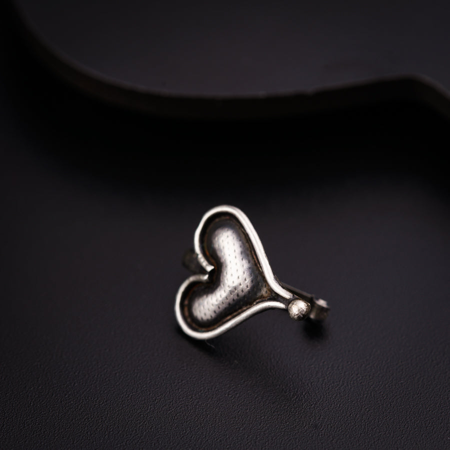 a heart shaped ring sitting on top of a black surface