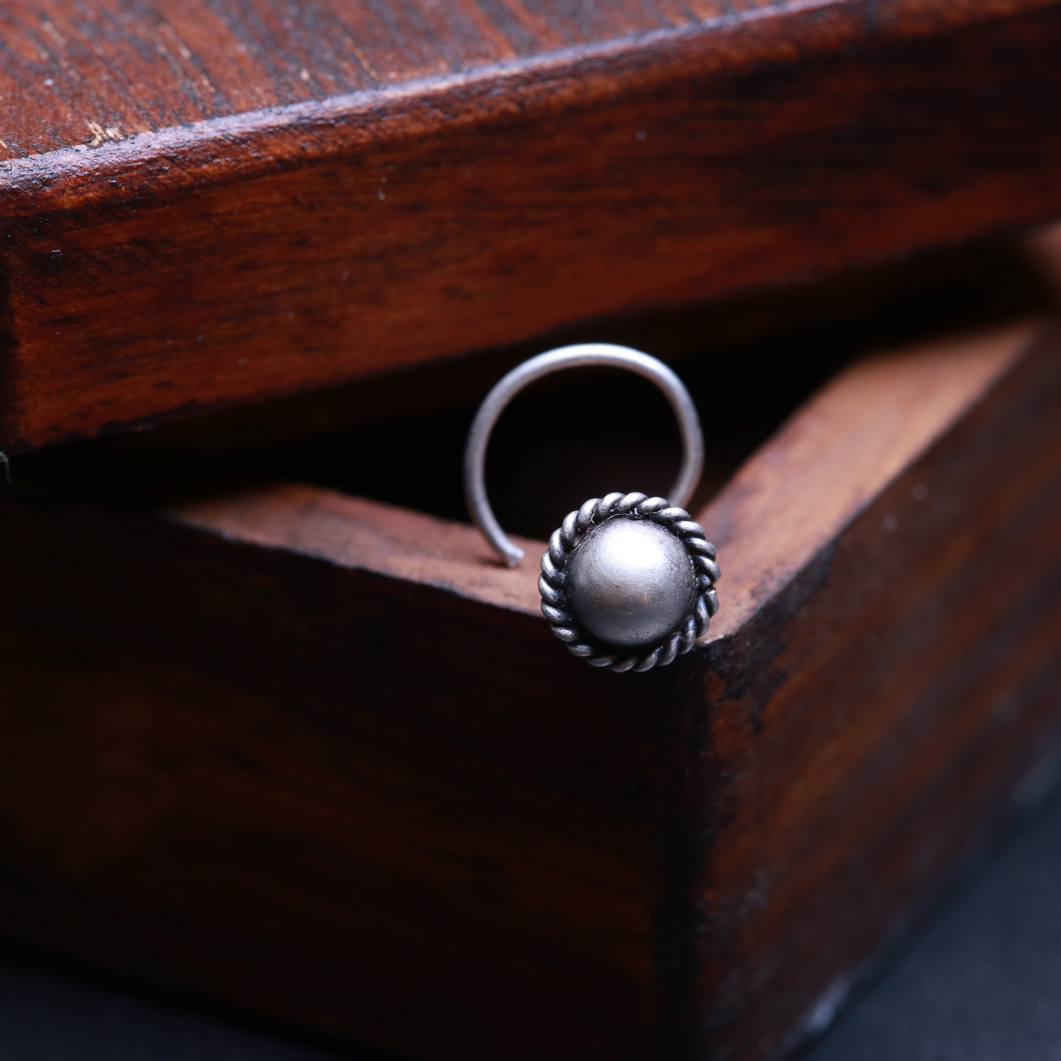 a silver ring sitting on top of a wooden box