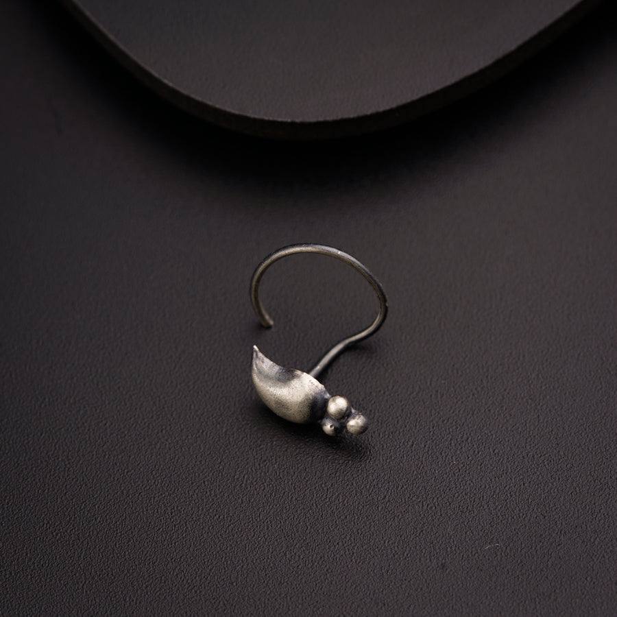 a pair of silver earrings sitting on top of a black surface