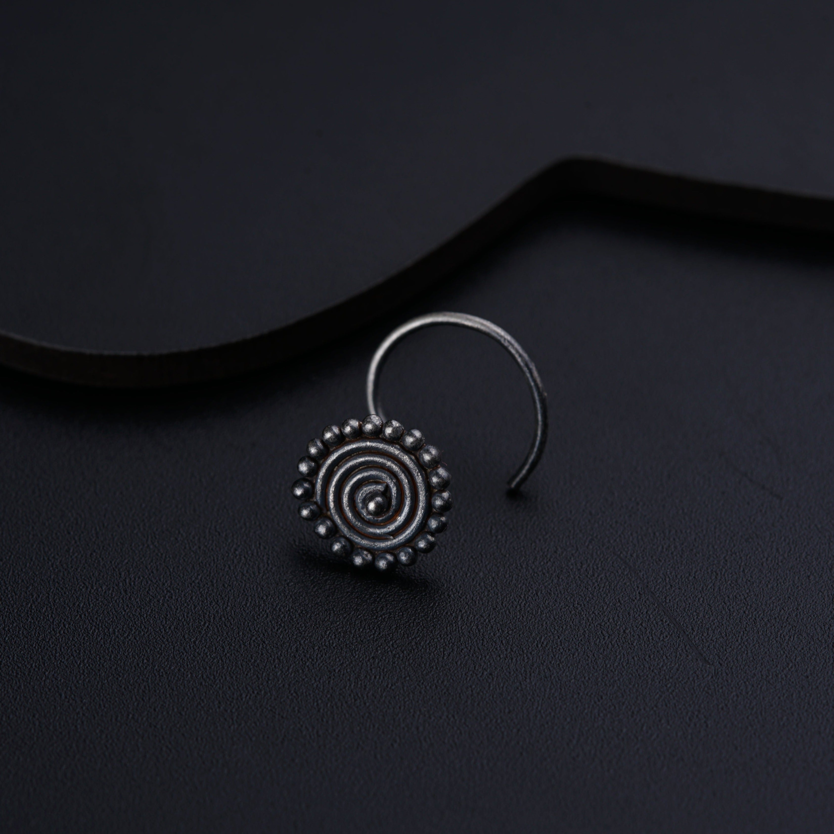 a pair of silver hoop earrings on a black surface