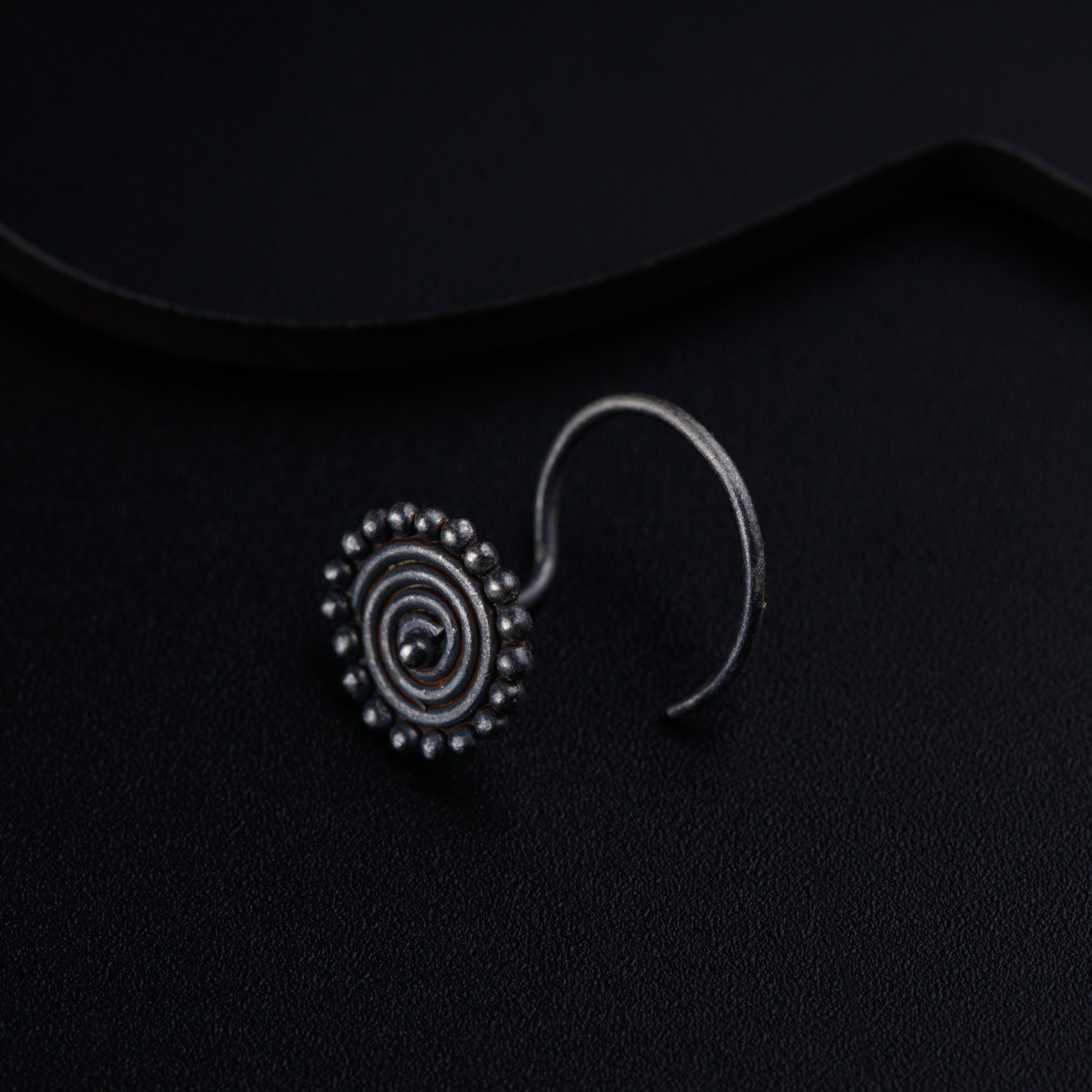 a pair of earrings sitting on top of a black surface