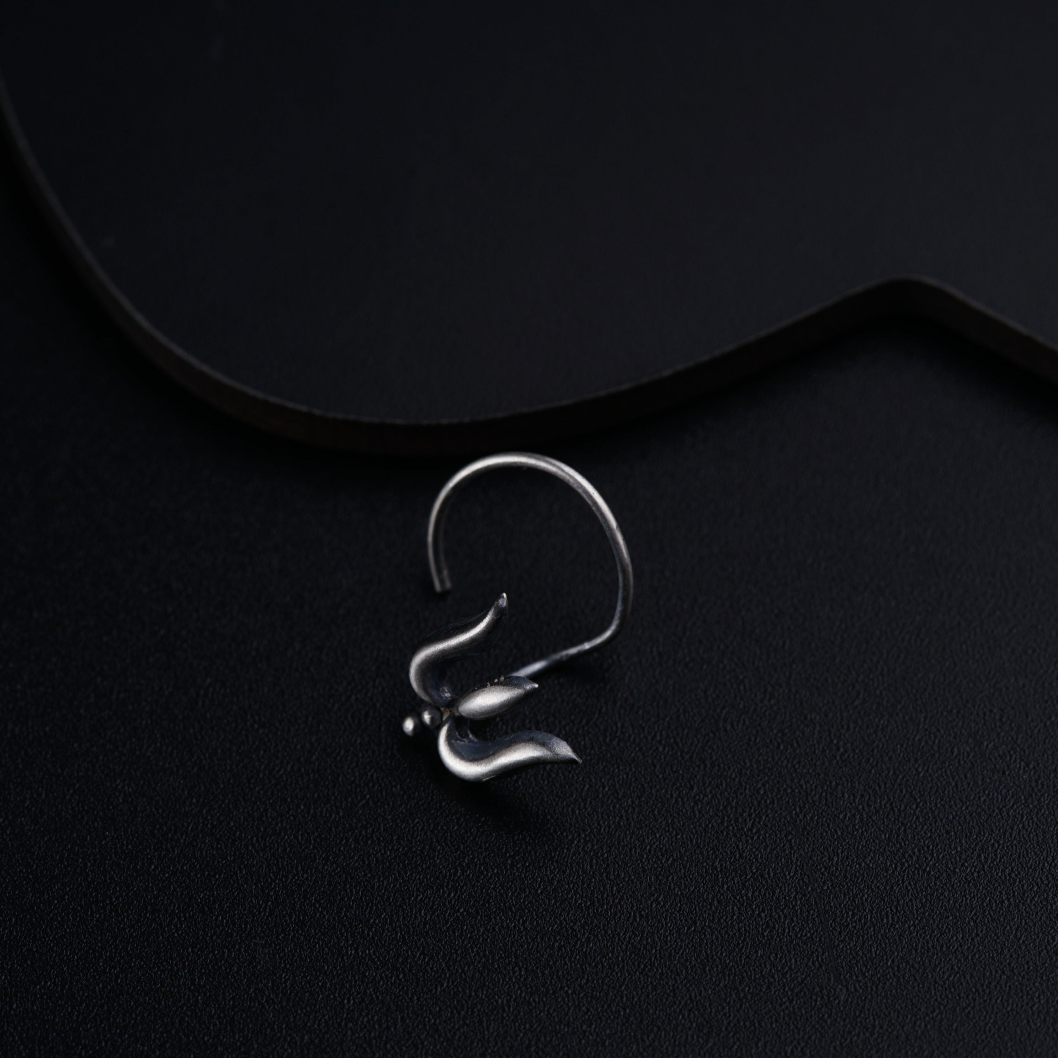 a pair of silver earrings on a black surface