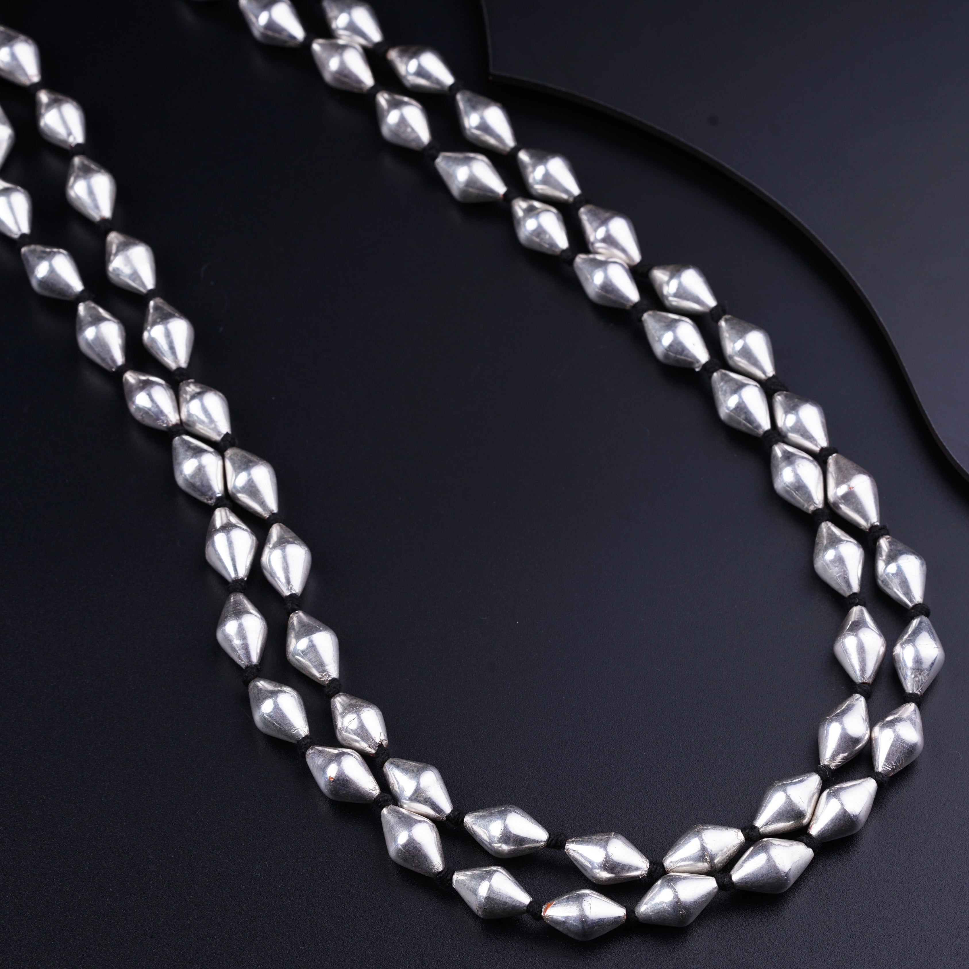 a long silver necklace on a black surface