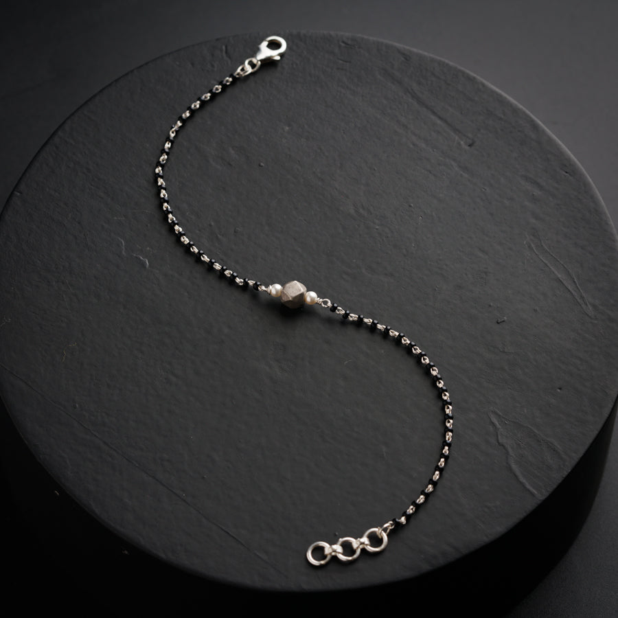 a silver beaded bracelet on a black background