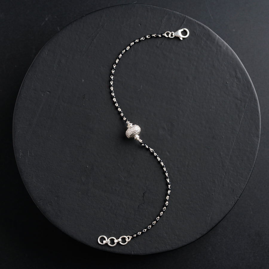 a silver beaded bracelet on a black plate