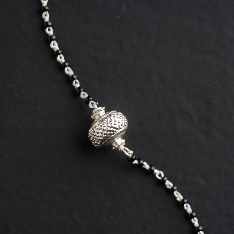 a silver beaded necklace with a ball on it