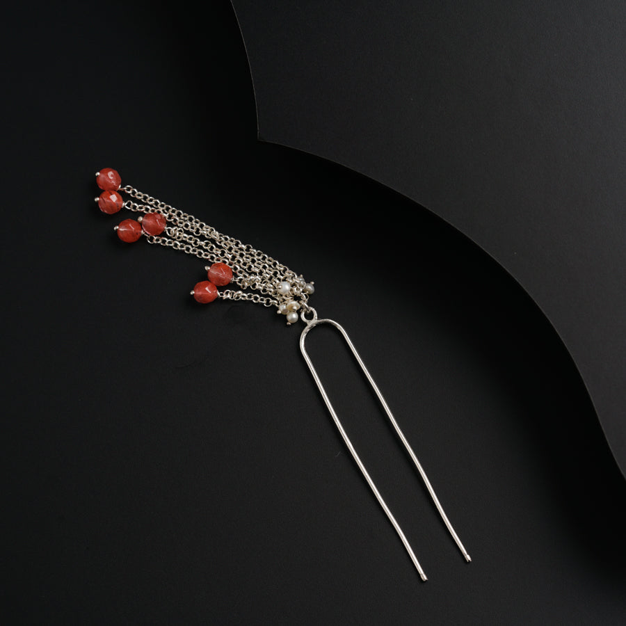 a pair of earrings with red beads hanging from them