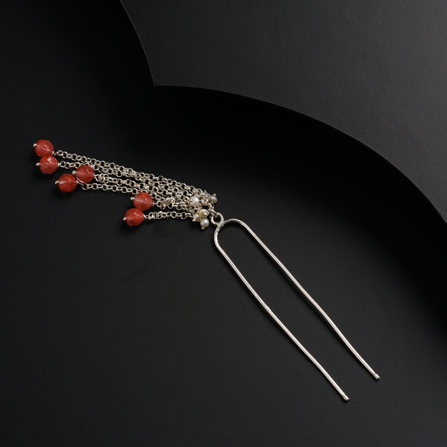 a pair of earrings with red beads hanging from them