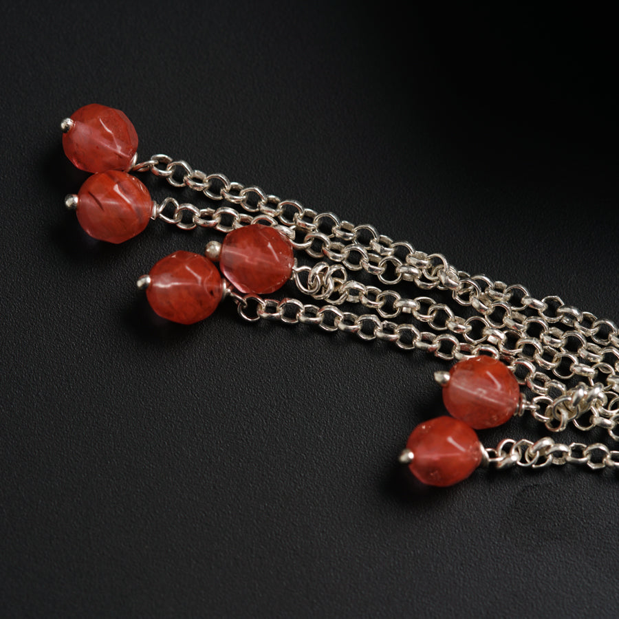 a close up of a chain with red beads
