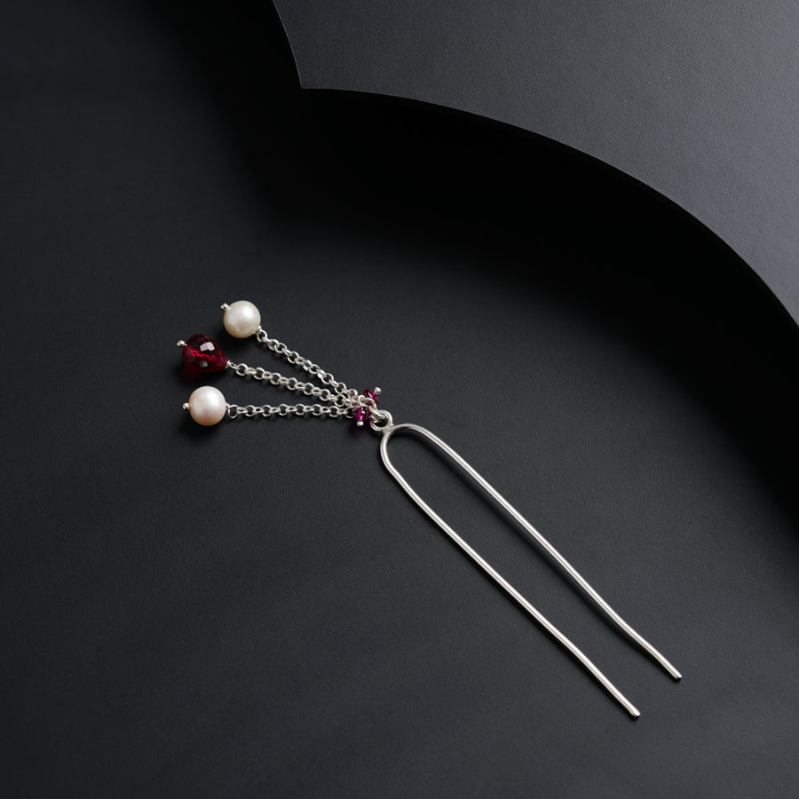 a pair of earrings with pearls hanging from them