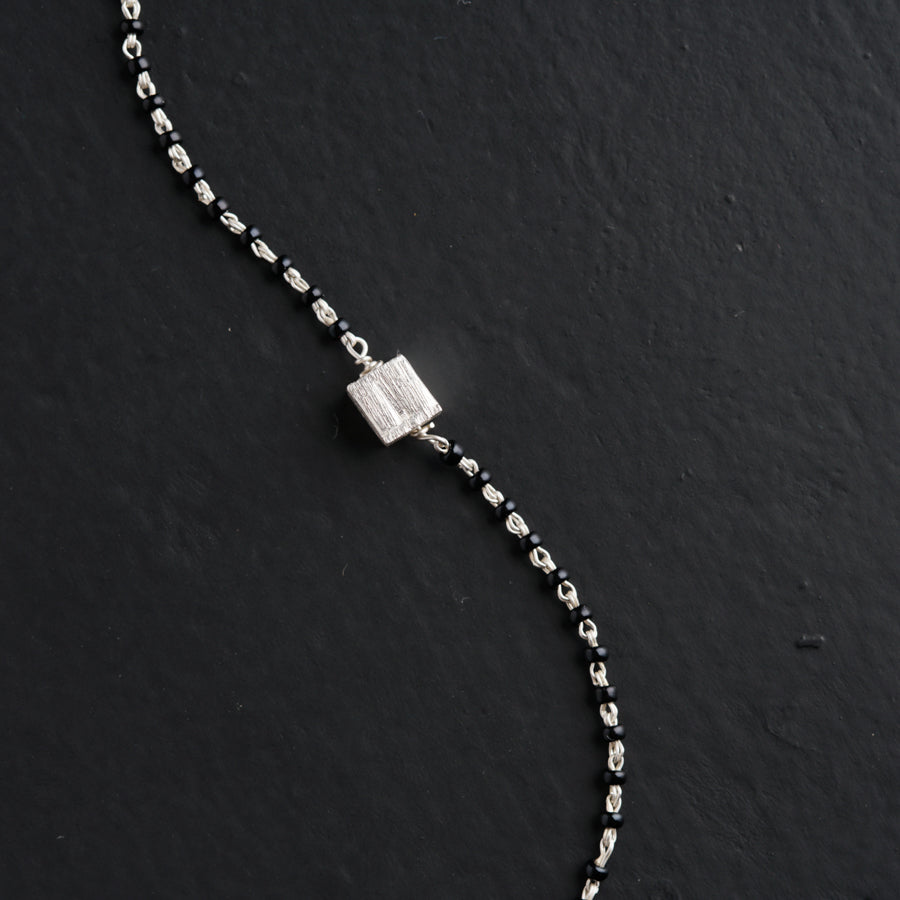 a silver bracelet with a square clasp on a black surface