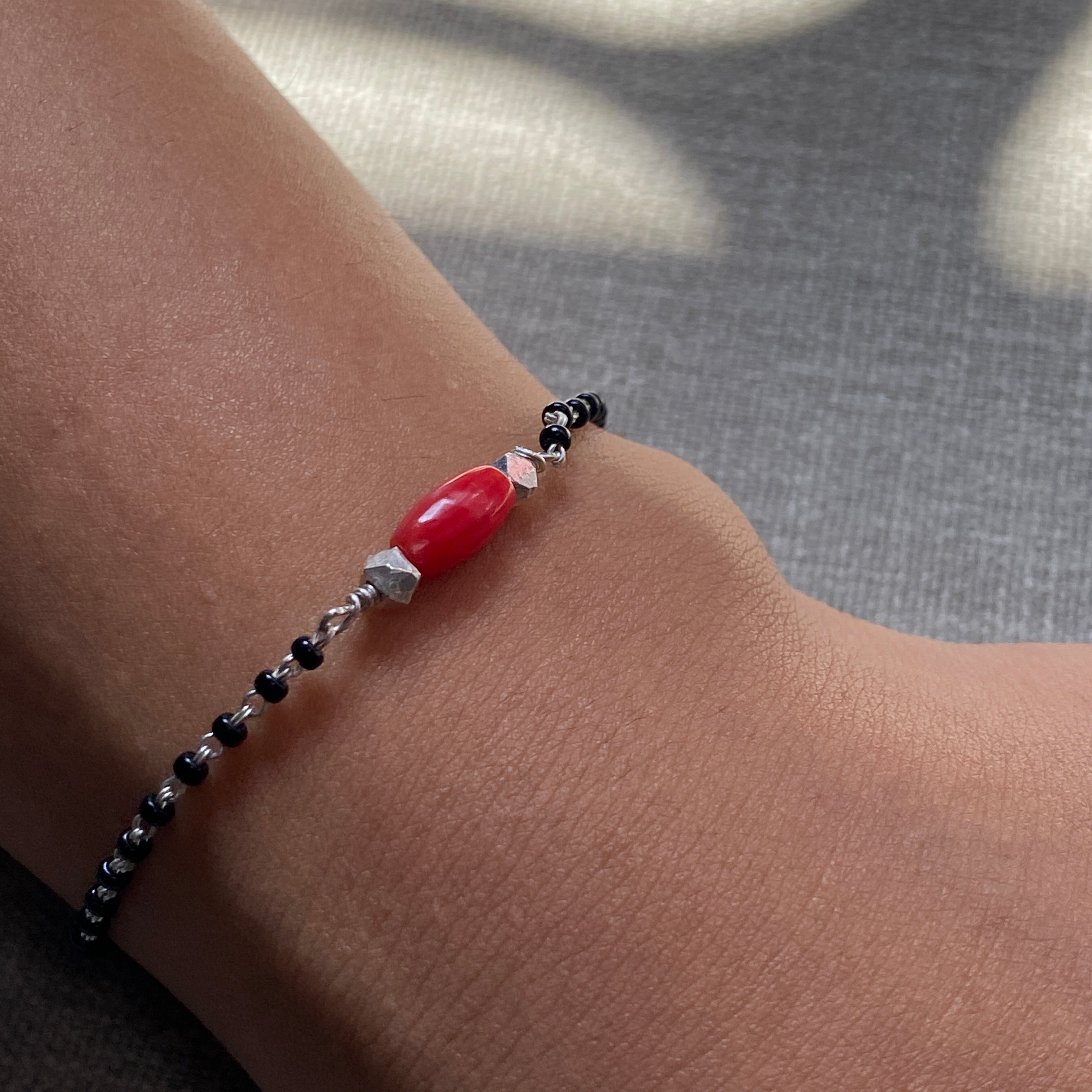 a woman's arm with a red beaded bracelet
