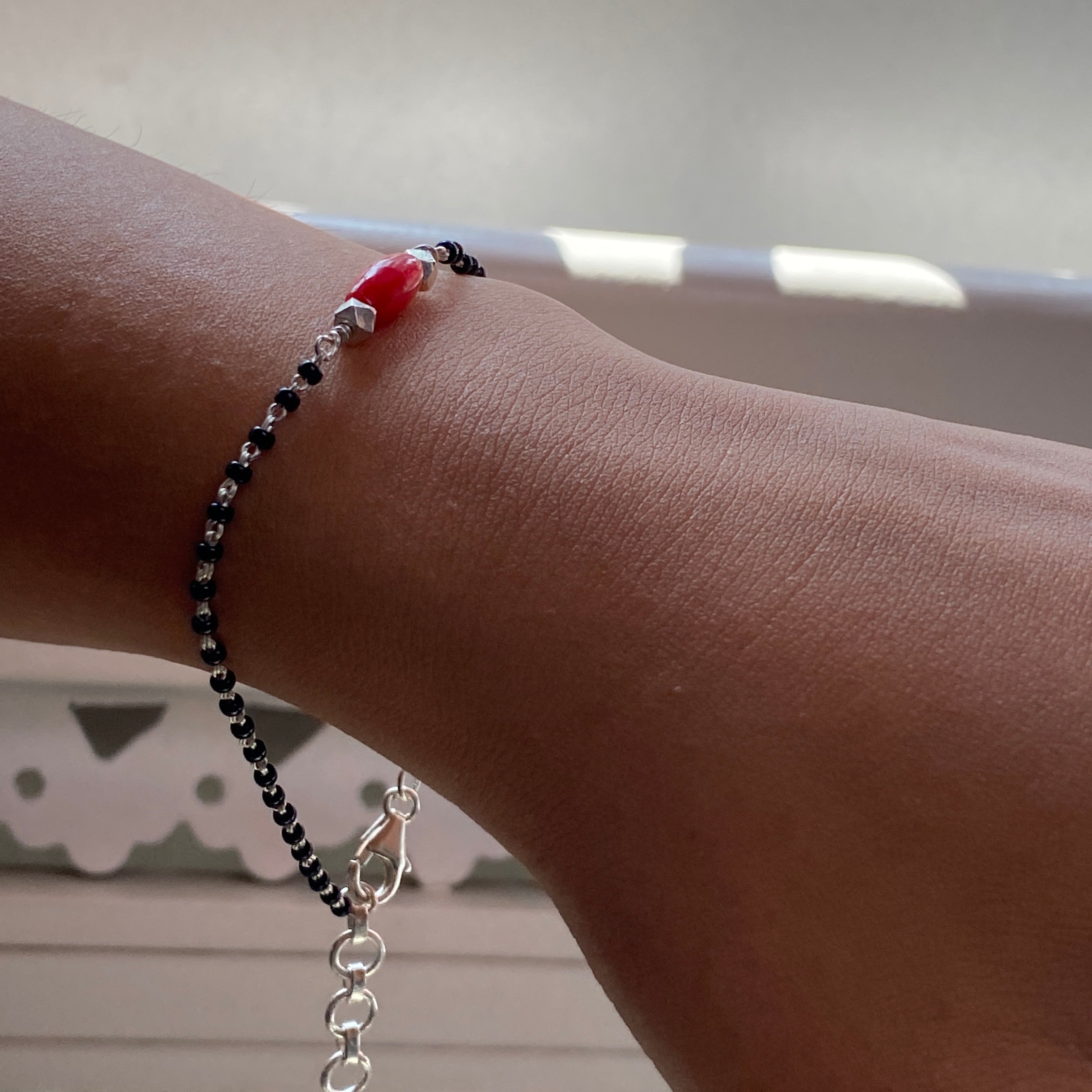 a woman's arm with a red and black beaded bracelet