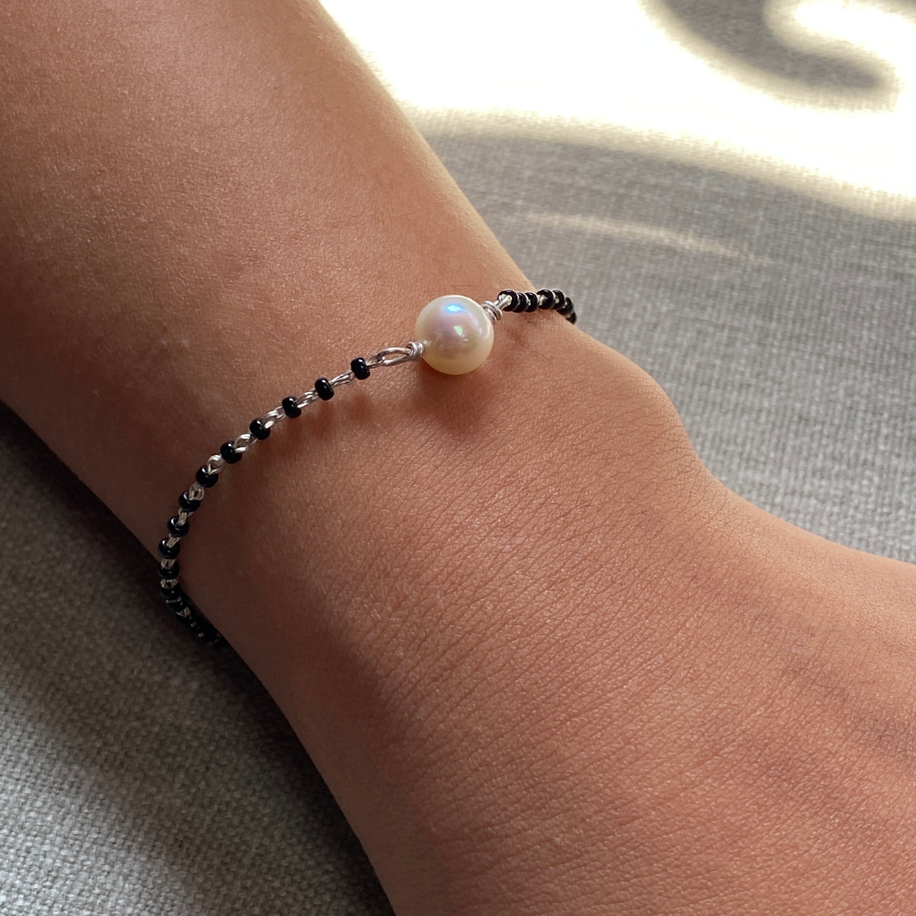 a person wearing a bracelet with a pearl on it