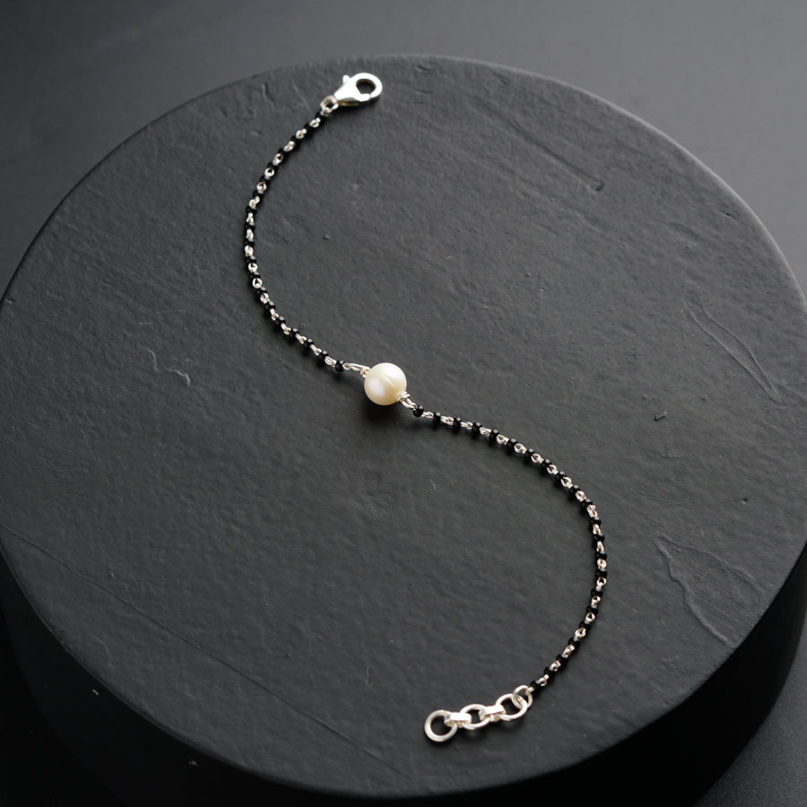 a silver bracelet with pearls and a chain