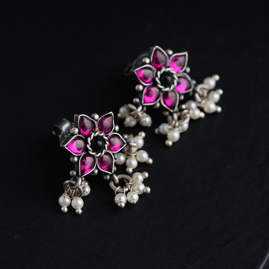 a pair of pink and white earrings on a black surface