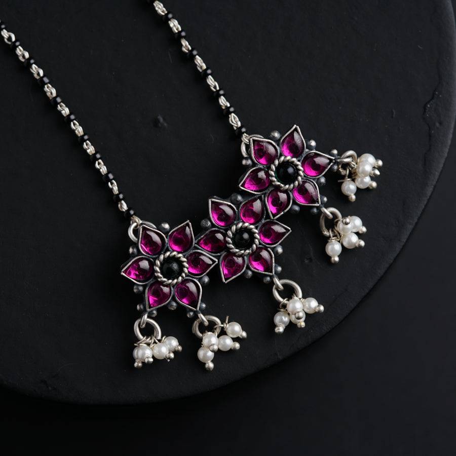 a necklace with pink and white beads on a black surface