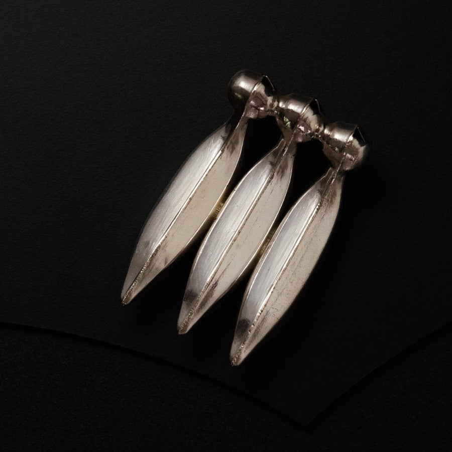 a pair of silver earrings sitting on top of a black surface