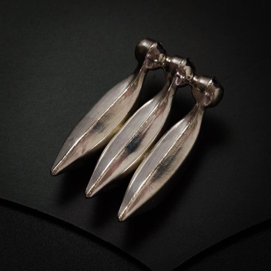 a pair of silver earrings sitting on top of a black surface