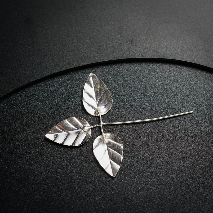 a pair of silver leaves on a black surface