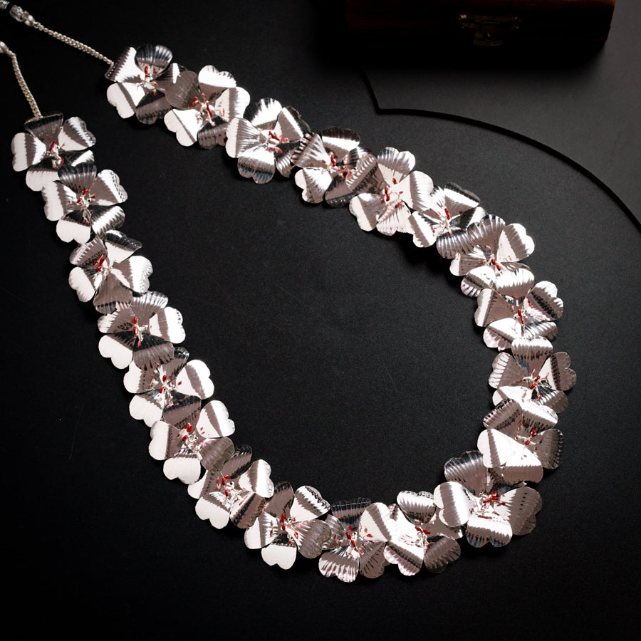 a necklace made of silver hearts on a black surface