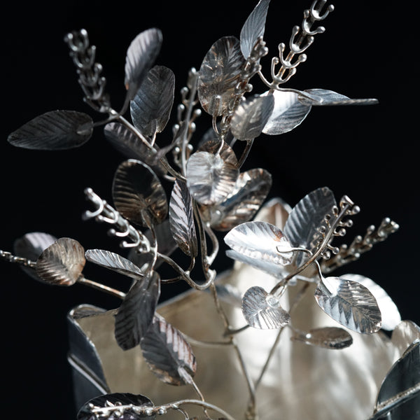 a silver vase filled with lots of silver leaves