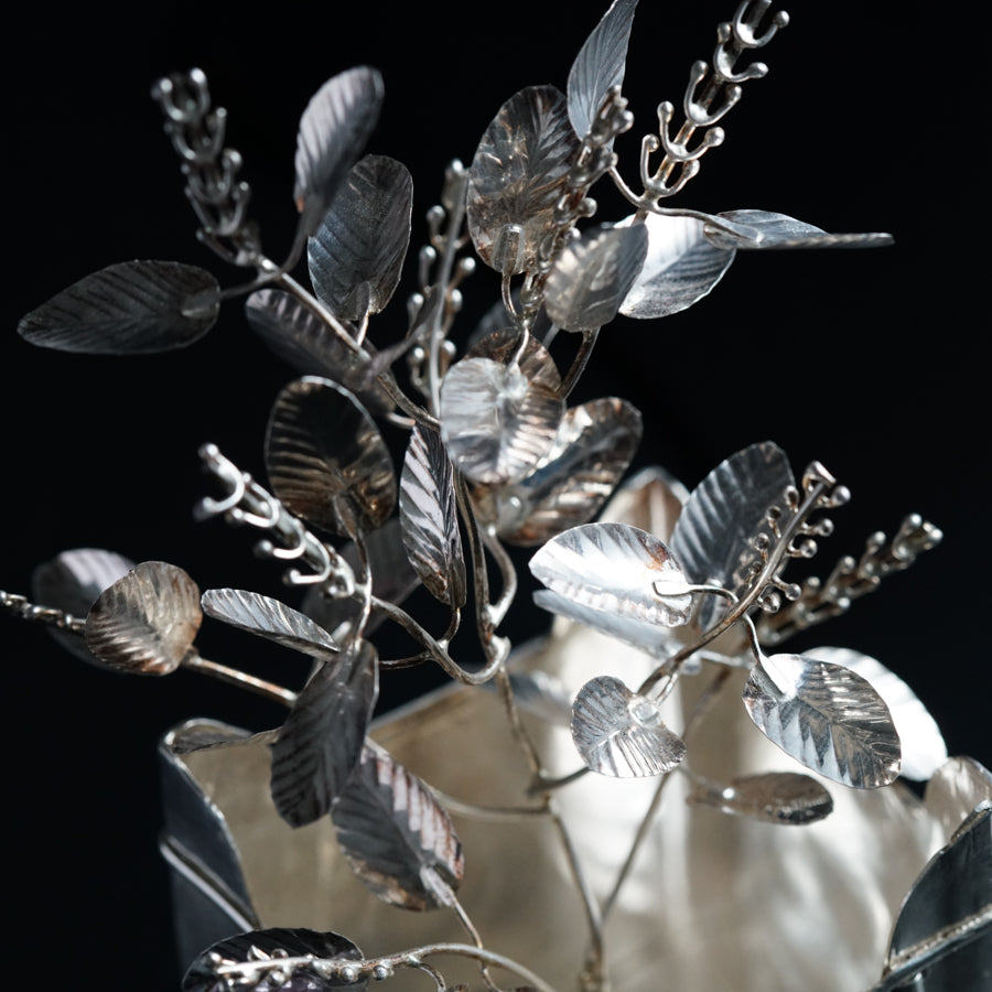 a silver vase filled with lots of silver leaves