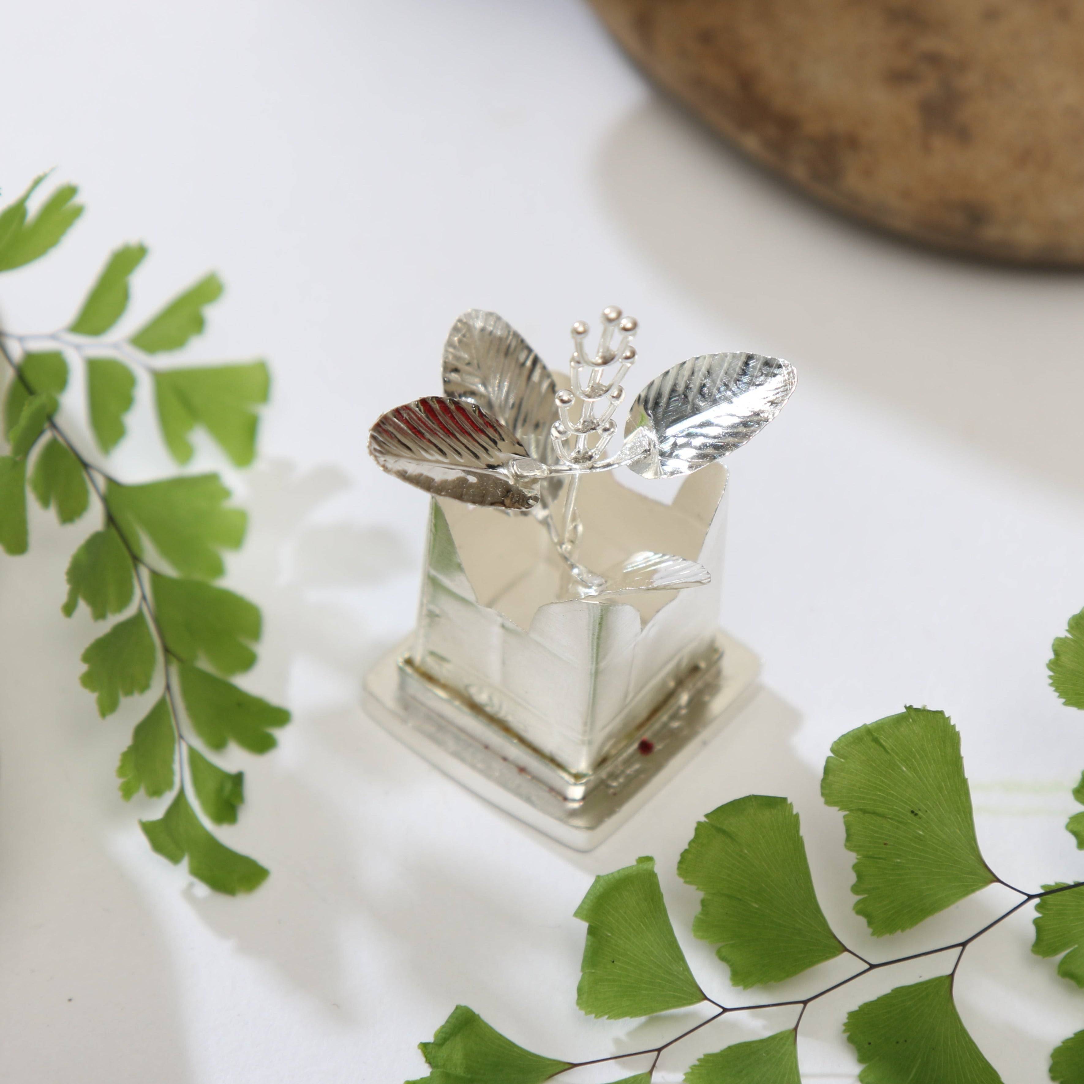 a small glass vase with a leaf decoration on it