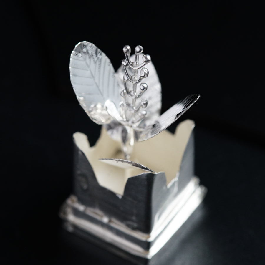 a silver object with a leaf on top of it