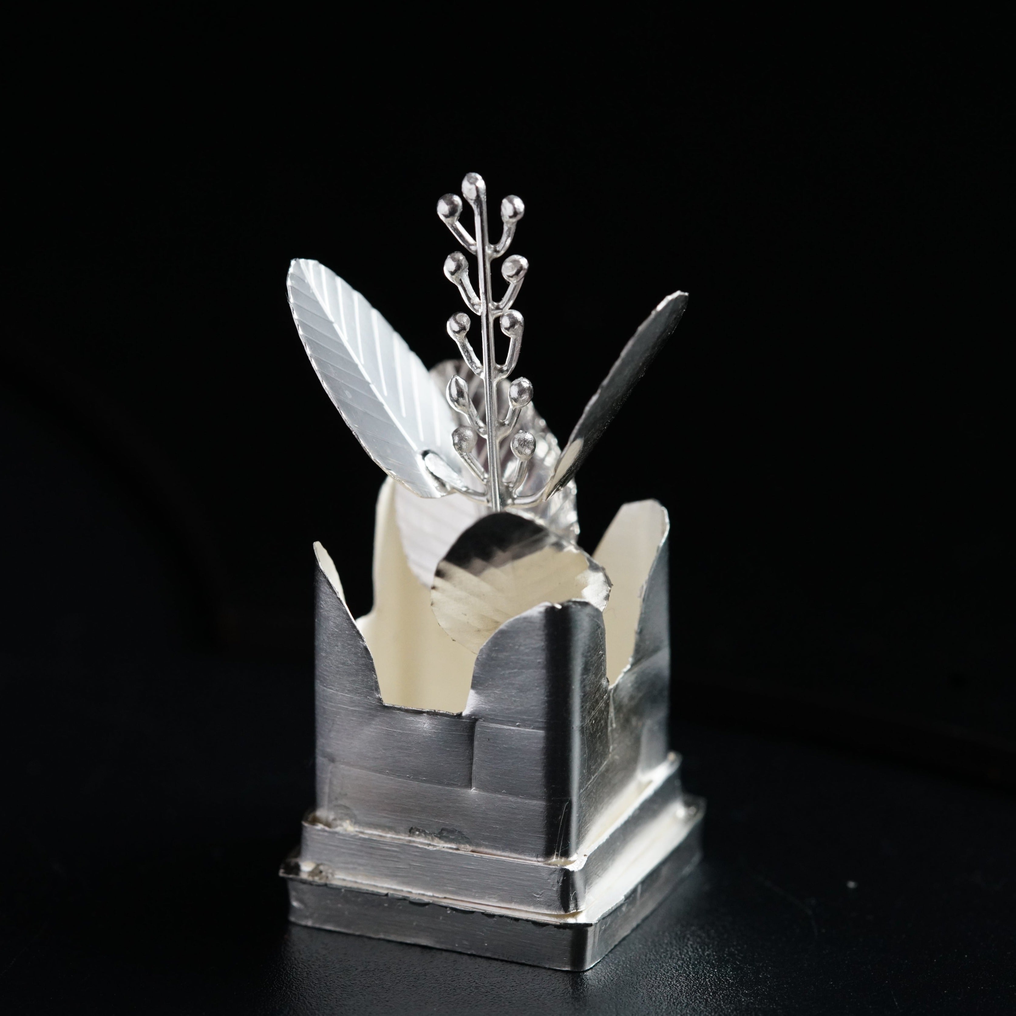 a silver object with a knife and a flower in it