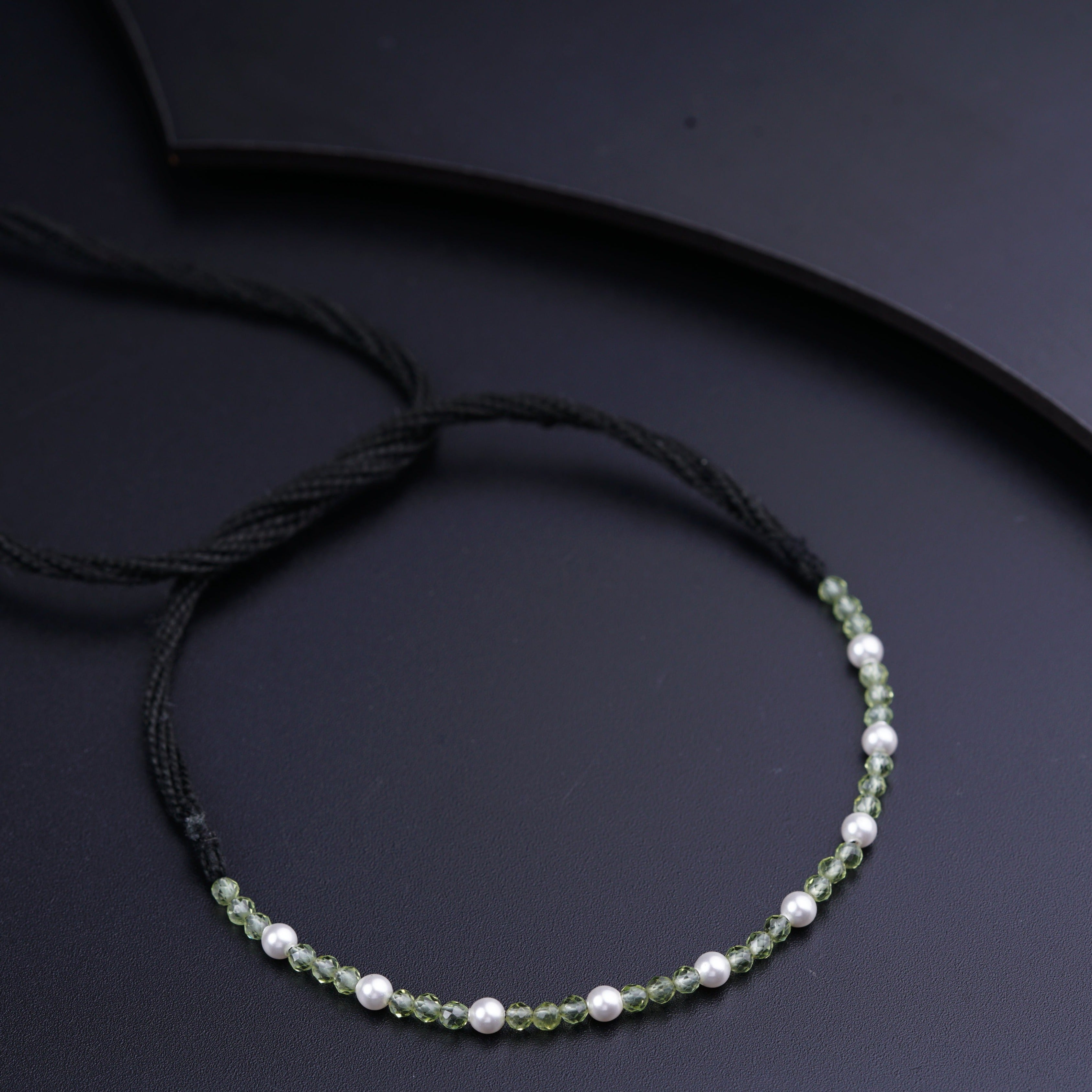 a green and white beaded necklace on a black surface