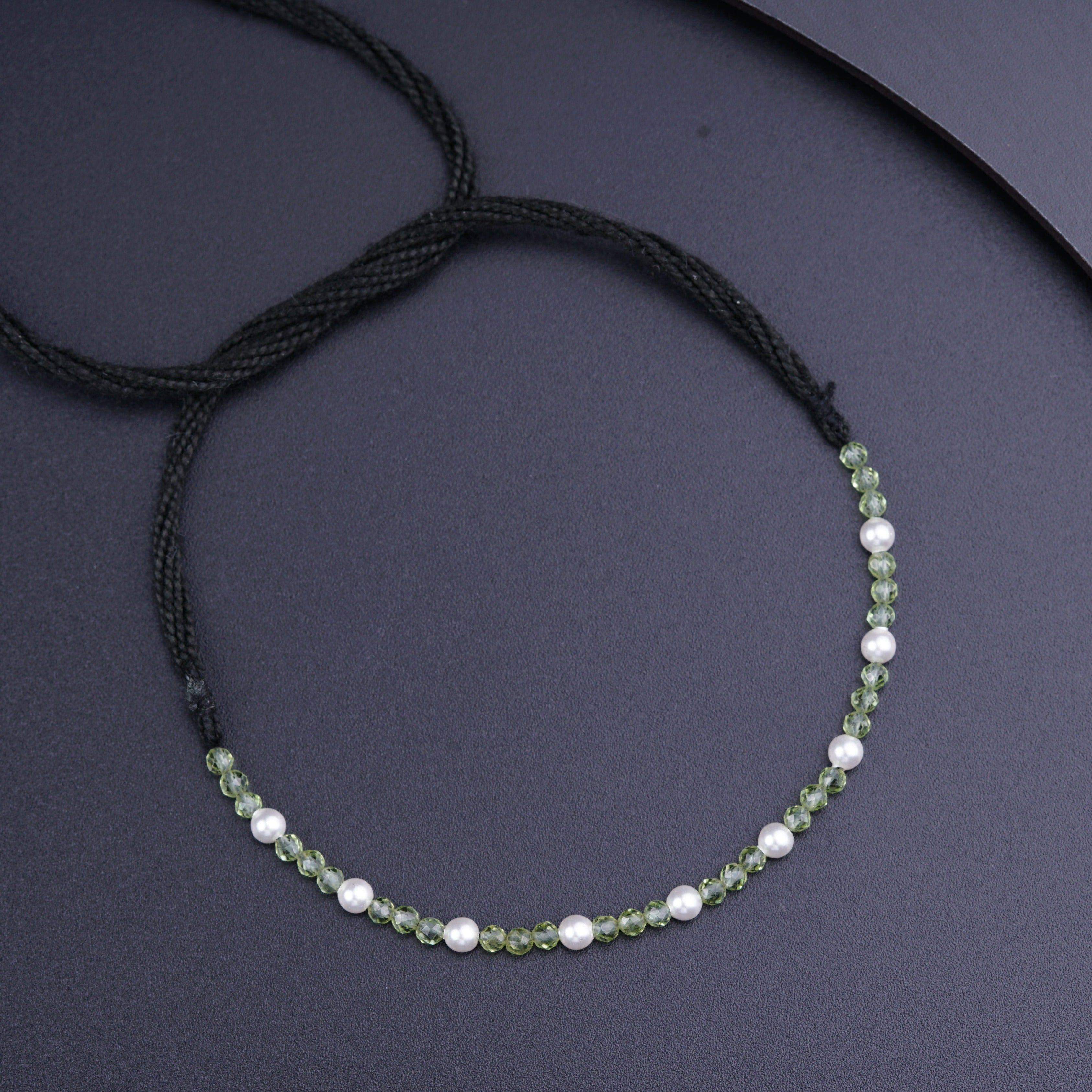 a green and white beaded necklace sitting on top of a table