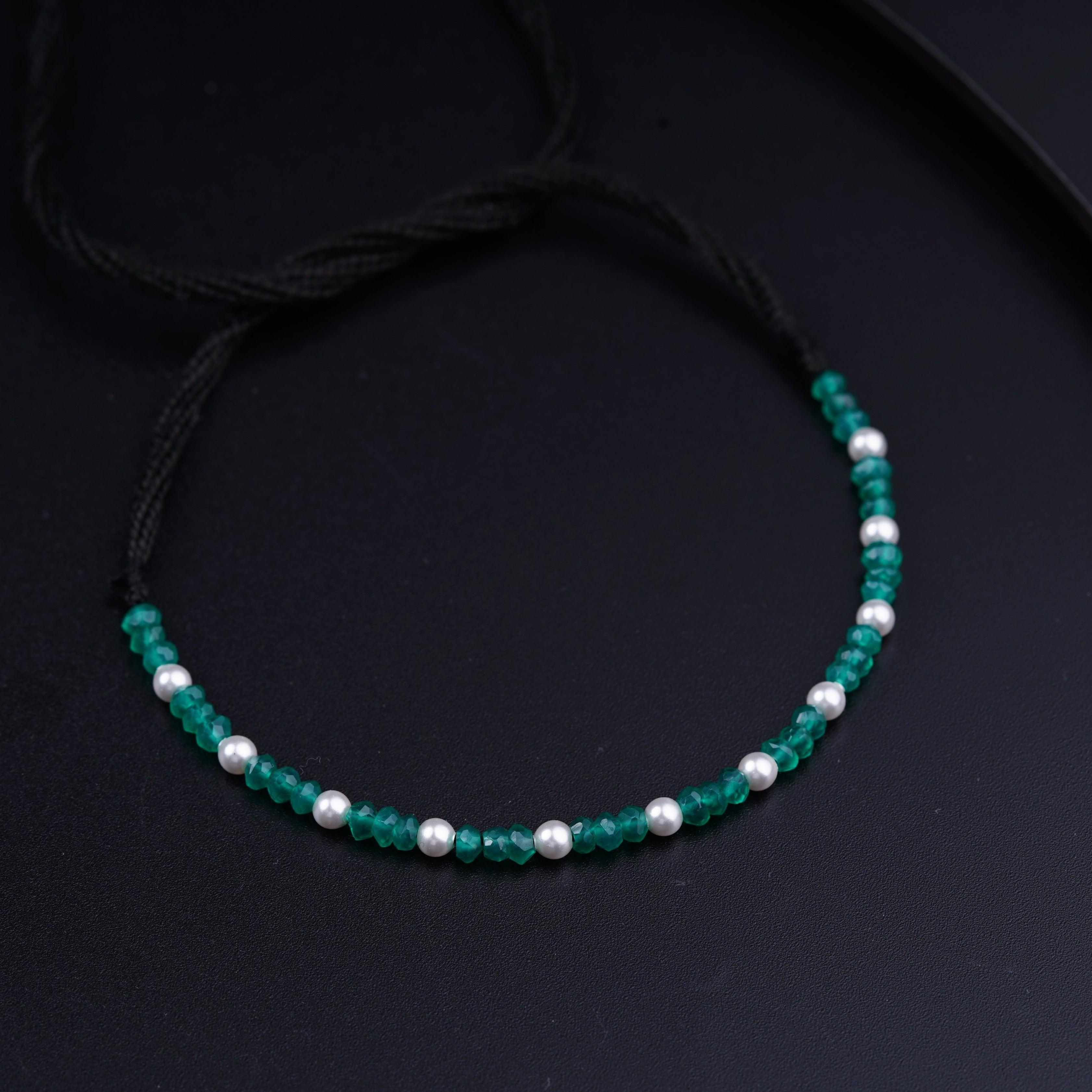 a green beaded bracelet with white pearls