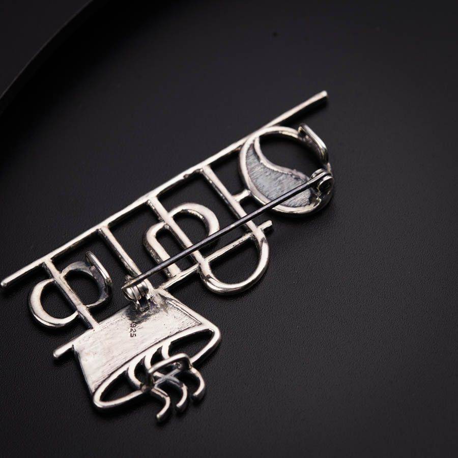 a silver brooch with the word bitch on it