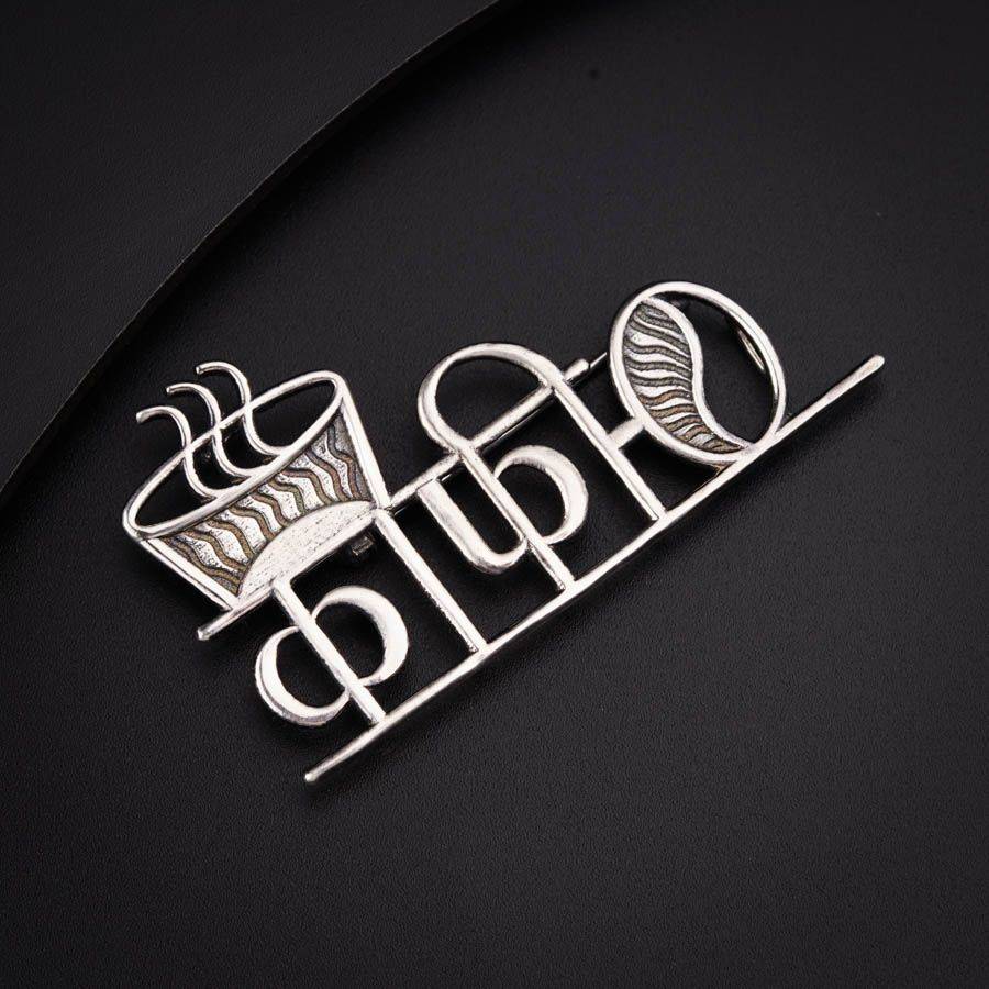 a silver brooch with a crown on top of it