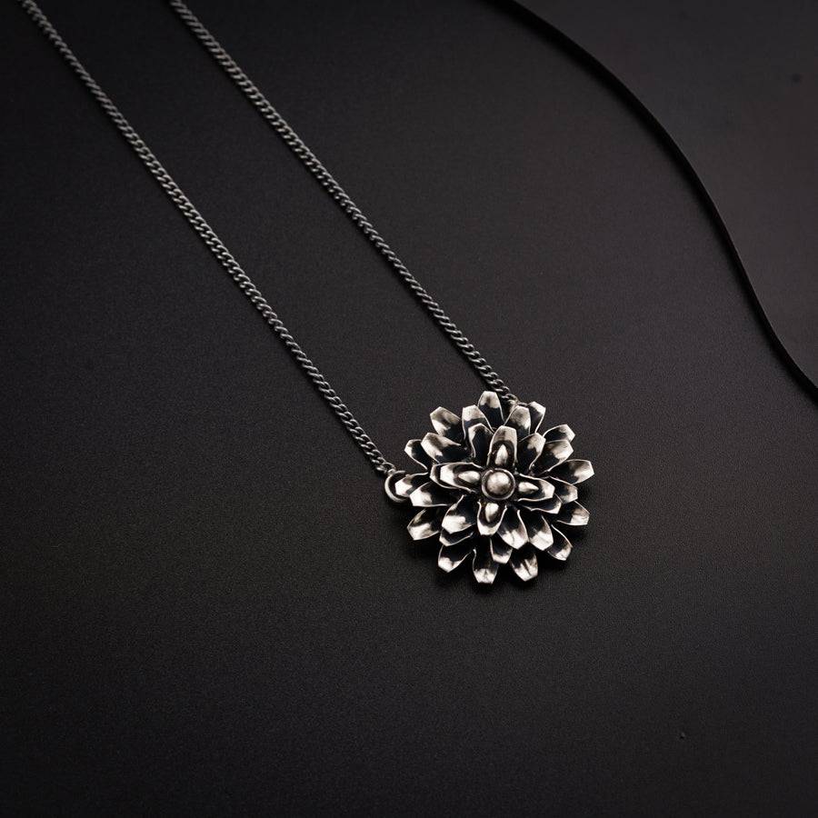 a necklace with a flower on a black background