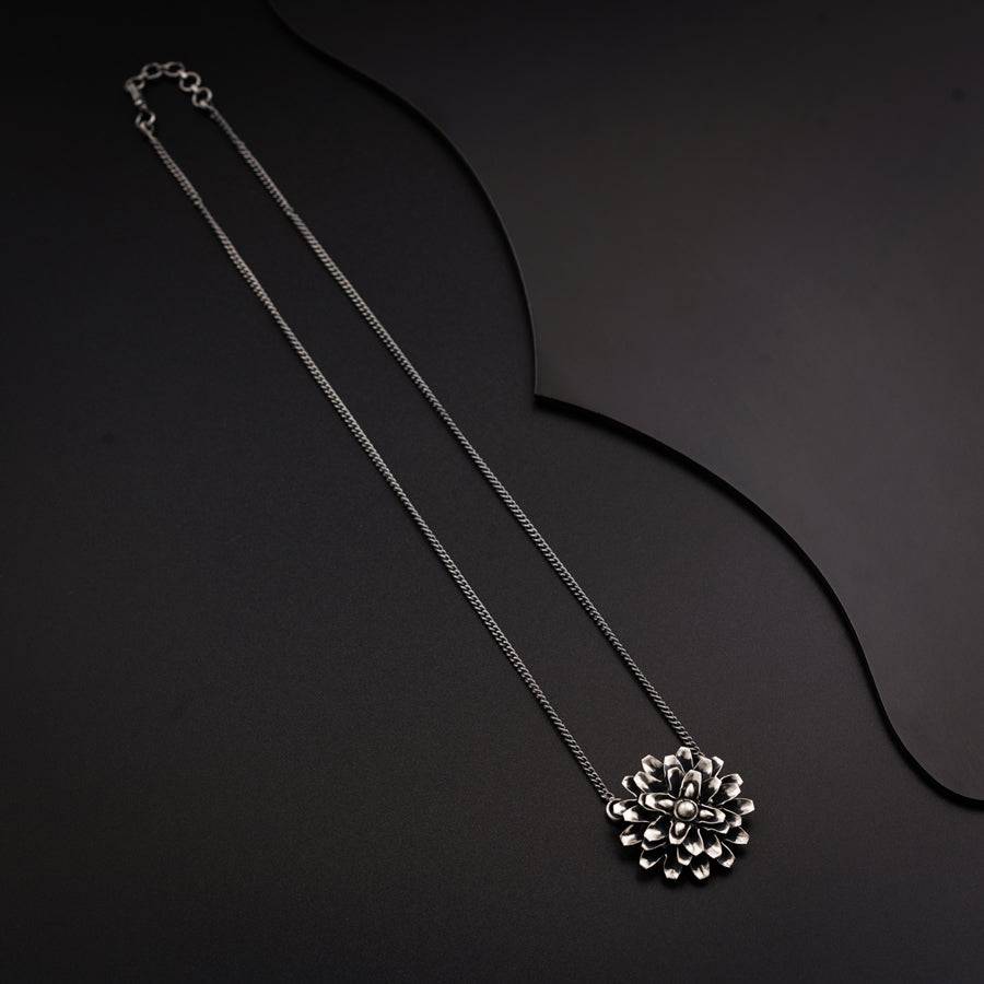 a silver necklace with a flower on it