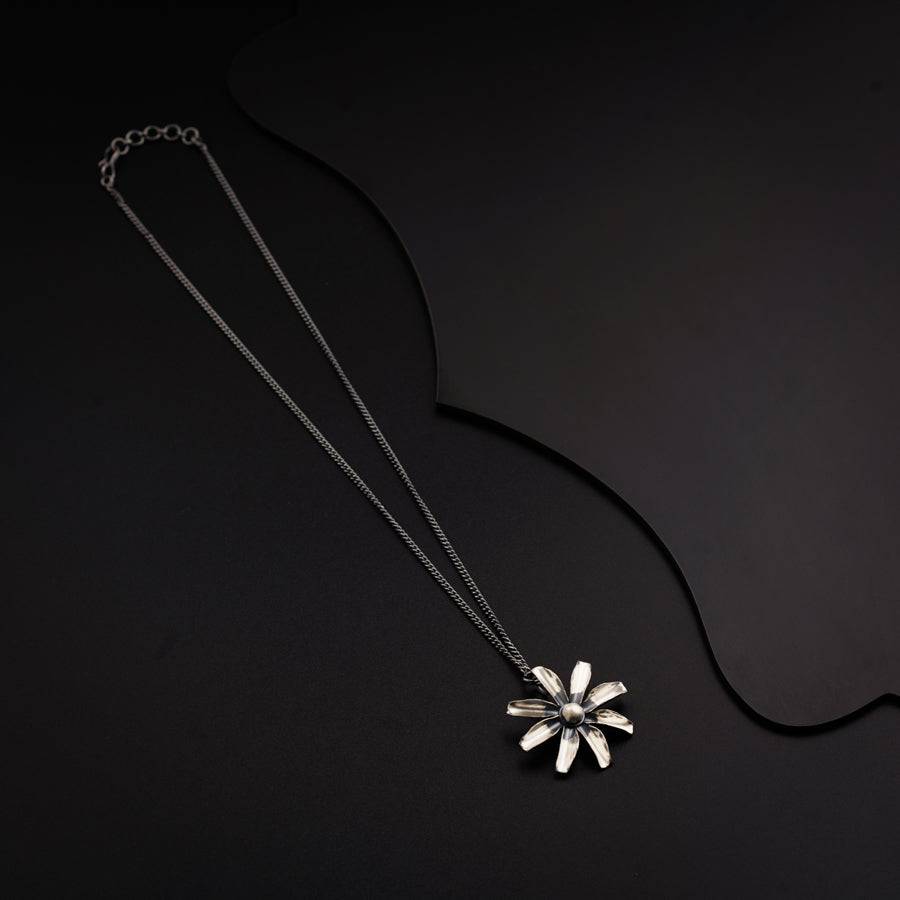 a necklace with a flower on a black background