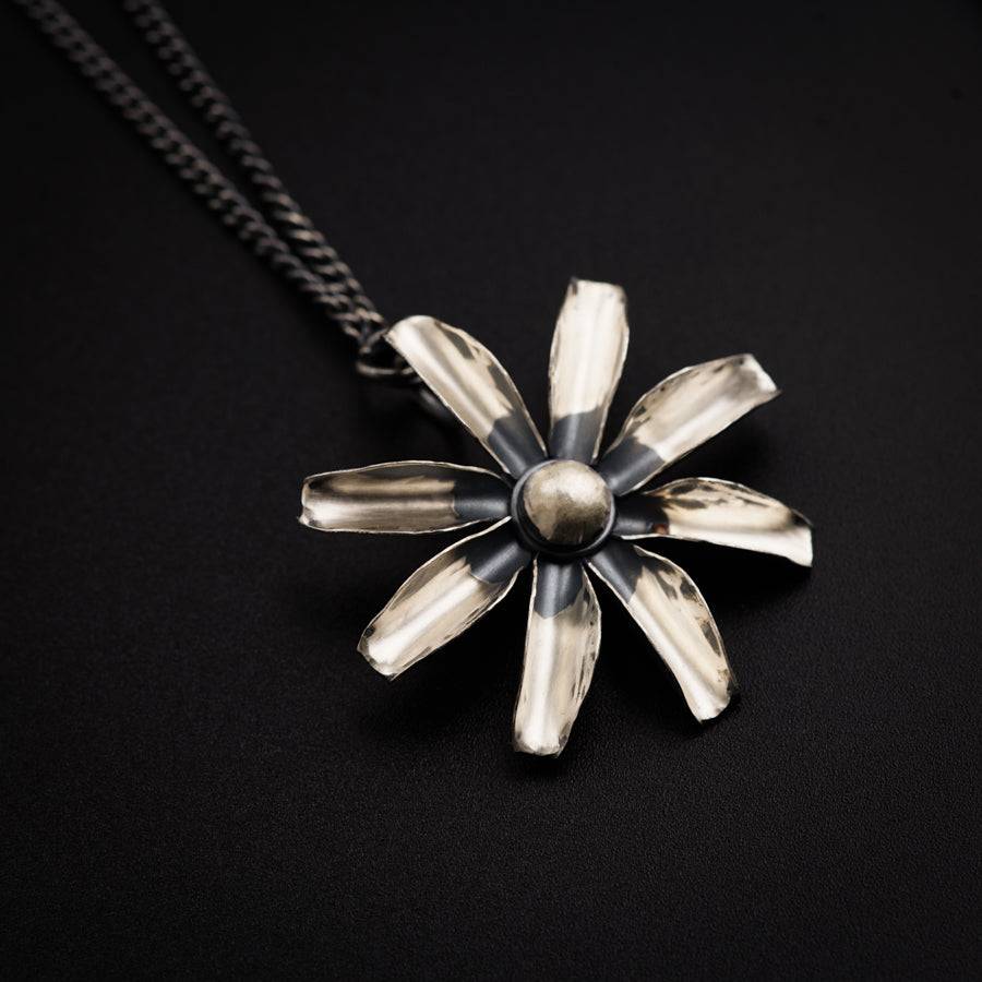 a silver and black flower pendant on a chain