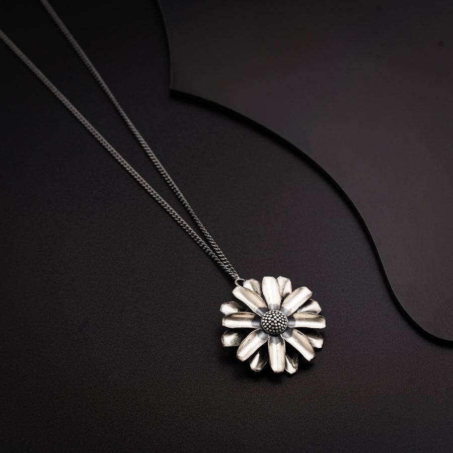 a necklace with a flower on a black background
