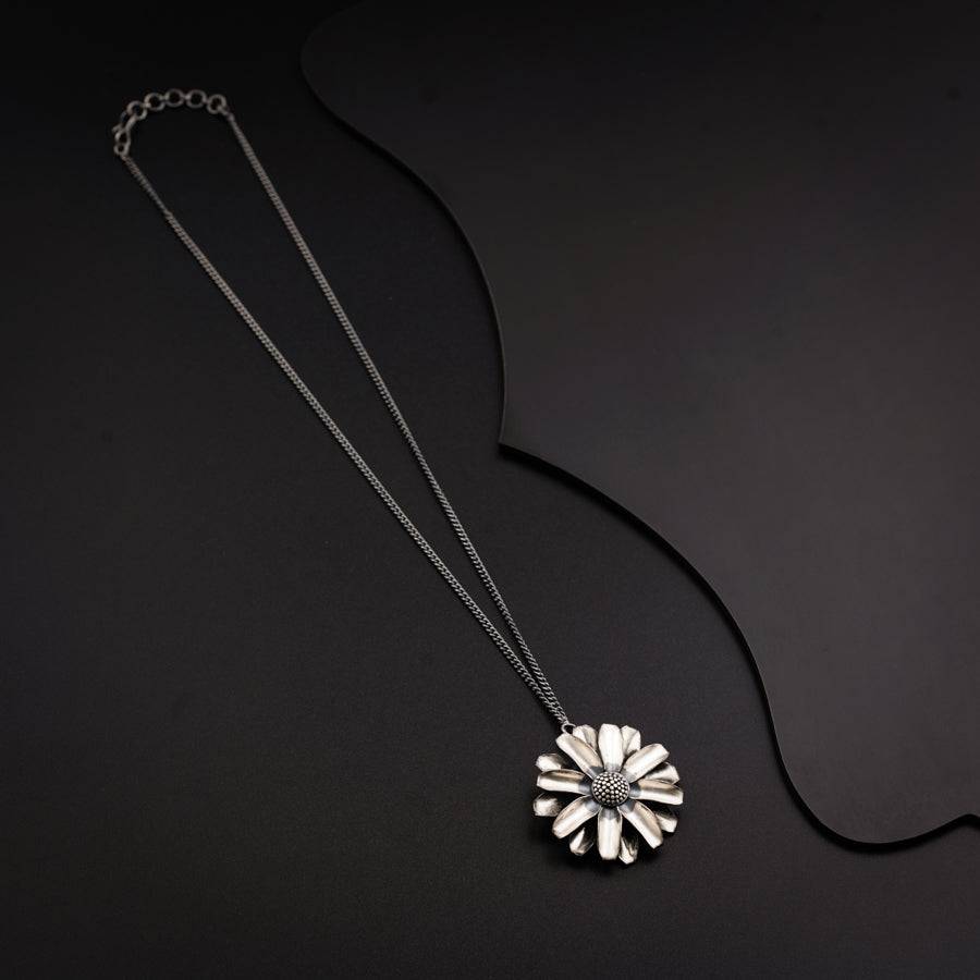 a necklace with a flower on a black background