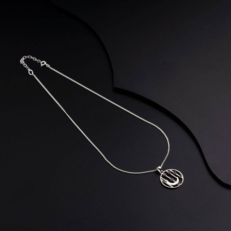 a silver necklace on a black surface