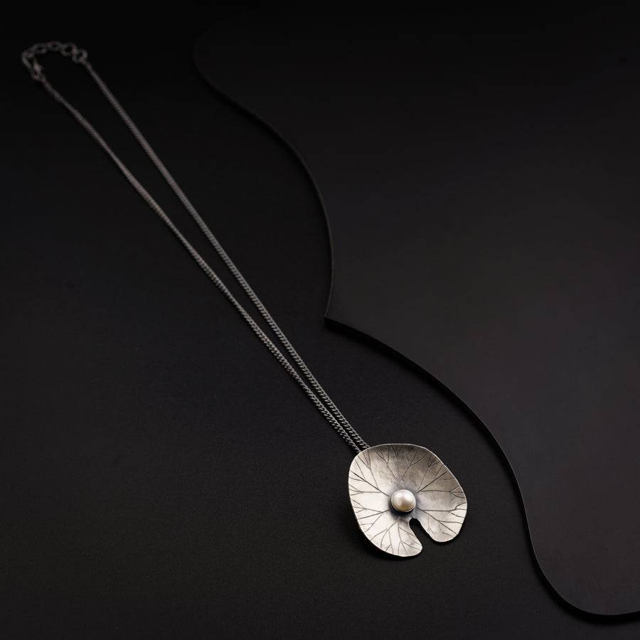a necklace with a silver flower on a black background