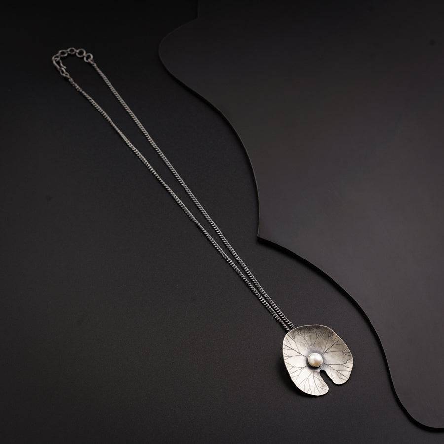a silver necklace with a flower on it