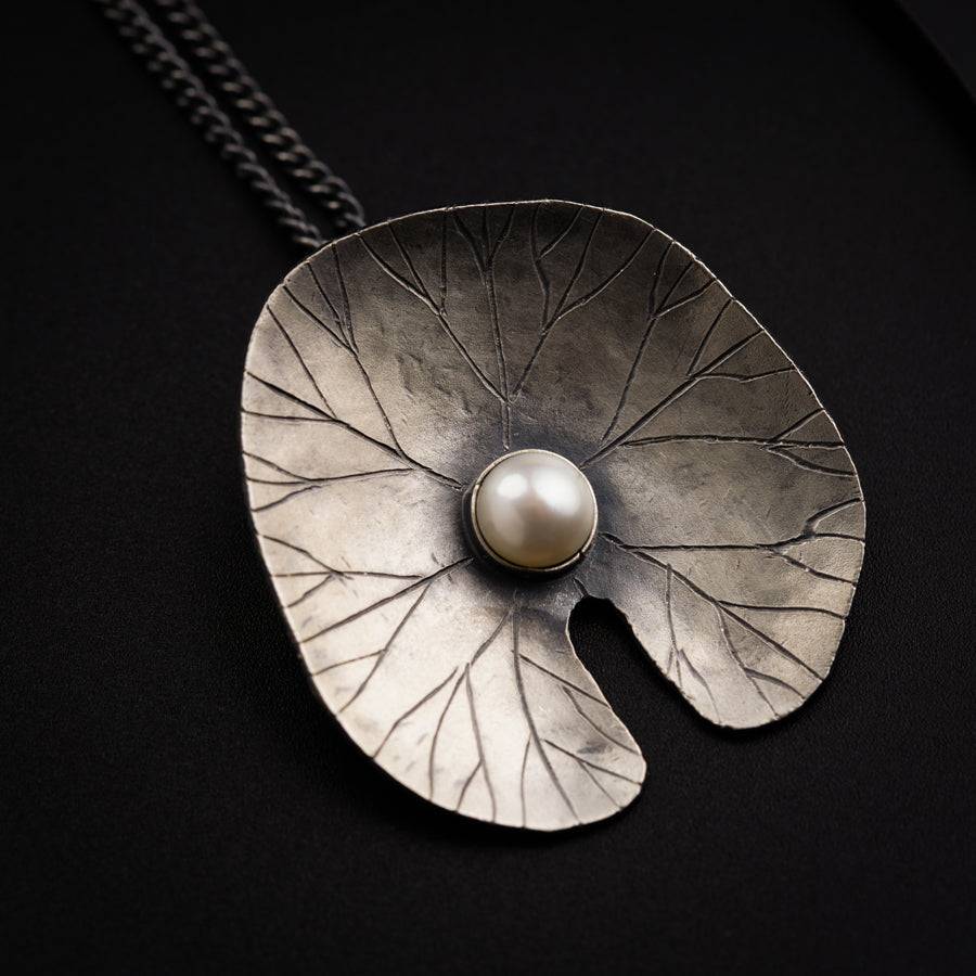 a large metal leaf with a pearl in the center