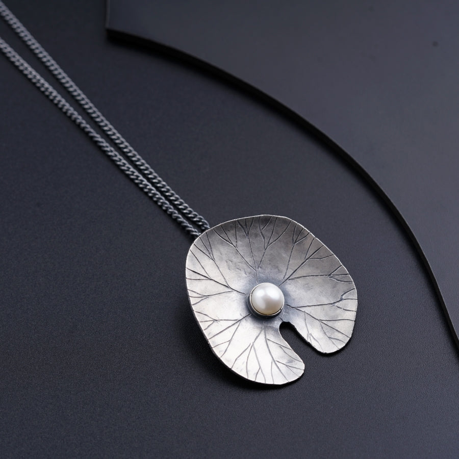a silver necklace with a pearl in the center